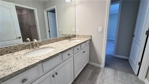 a bathroom with a granite countertop double vanity sink and a mirror