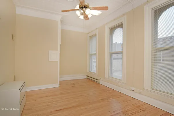 an empty room with wooden floor fan and windows