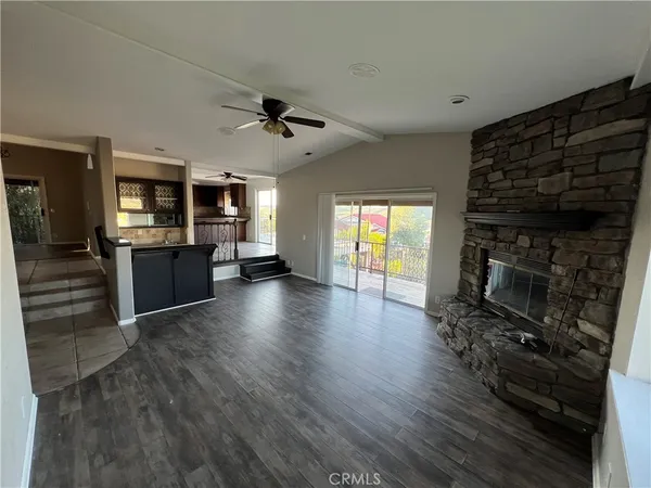 a living room with stainless steel appliances furniture a fireplace and wooden floor