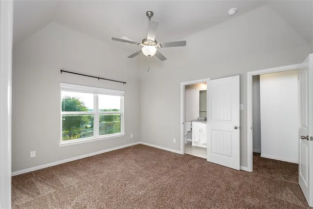 an empty room with chandelier fan and windows