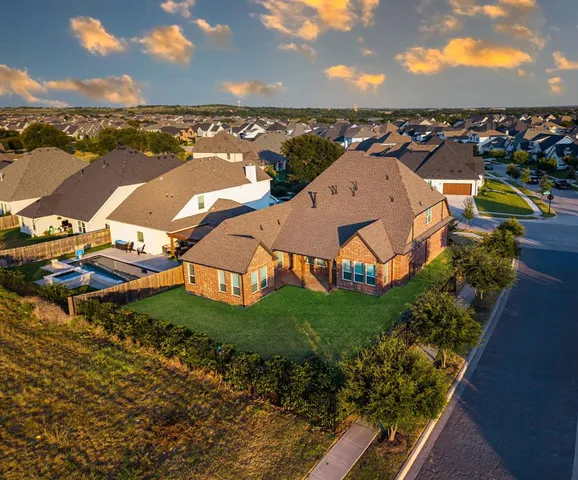 a view of a big house with a big yard and large trees
