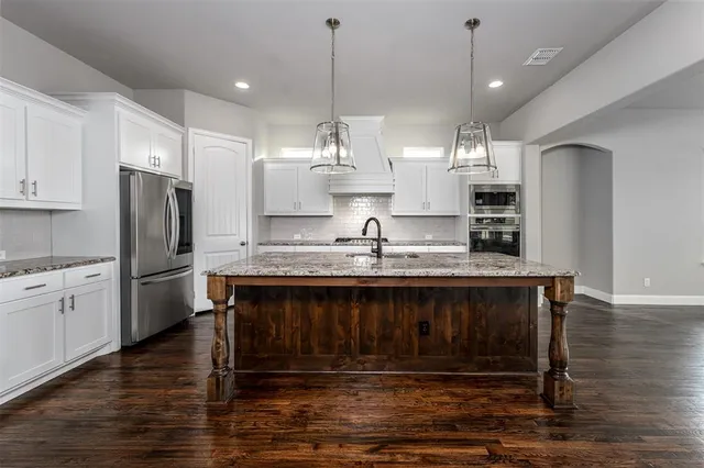 a kitchen with kitchen island granite countertop a sink cabinets and stainless steel appliances