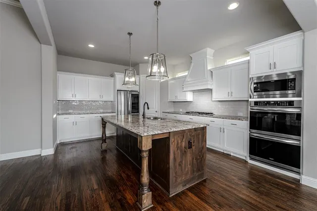 a kitchen with kitchen island granite countertop a sink cabinets and stainless steel appliances