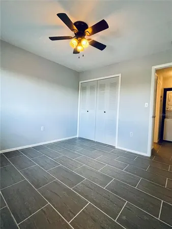 a view of an empty room with wooden floor and a ceiling fan