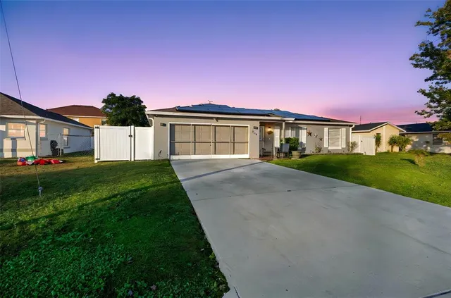 a view of house in front of a big yard with large trees