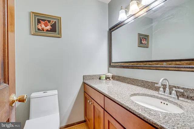 a bathroom with a granite countertop sink mirror vanity and toilet