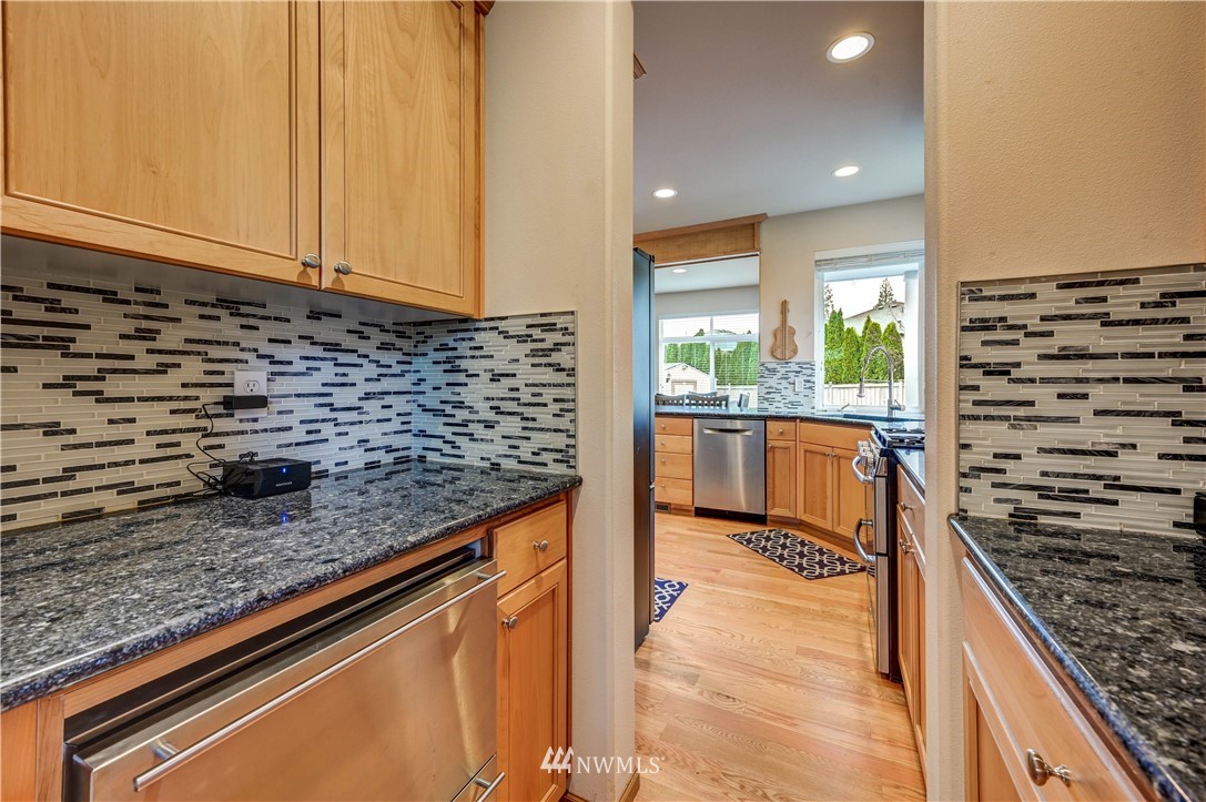5719 Northeast 3rd Street Renton, WA 98059 - Photo 13 of 40 a kitchen with stainless steel appliances kitchen island granite countertop a stove and a sink
