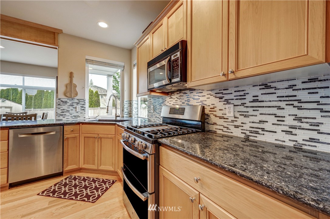 5719 Northeast 3rd Street Renton, WA 98059 - Photo 14 of 40 a kitchen with stainless steel appliances granite countertop a stove a sink and a microwave