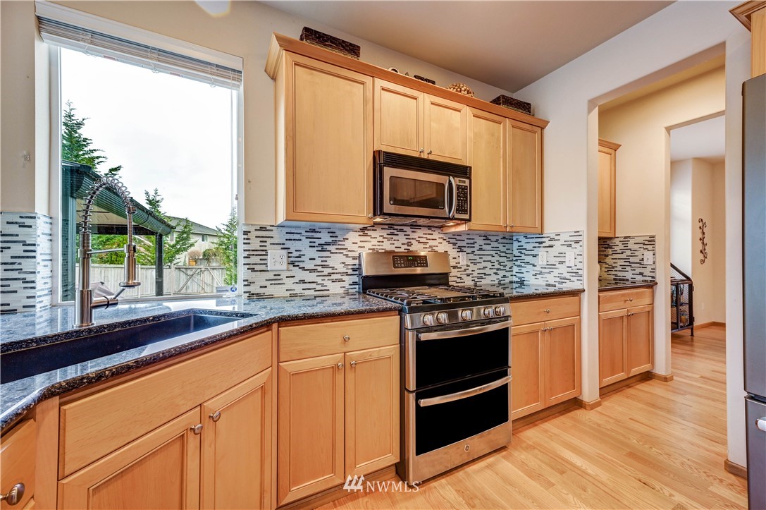 5719 Northeast 3rd Street Renton, WA 98059 - Photo 17 of 40 a kitchen with stainless steel appliances granite countertop a stove sink and microwave