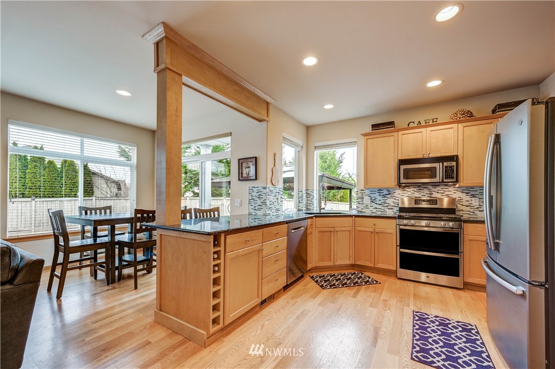 5719 Northeast 3rd Street Renton, WA 98059 - Photo 18 of 40 a kitchen with stainless steel appliances granite countertop a stove top oven a sink dishwasher a dining table and chairs with wooden floor