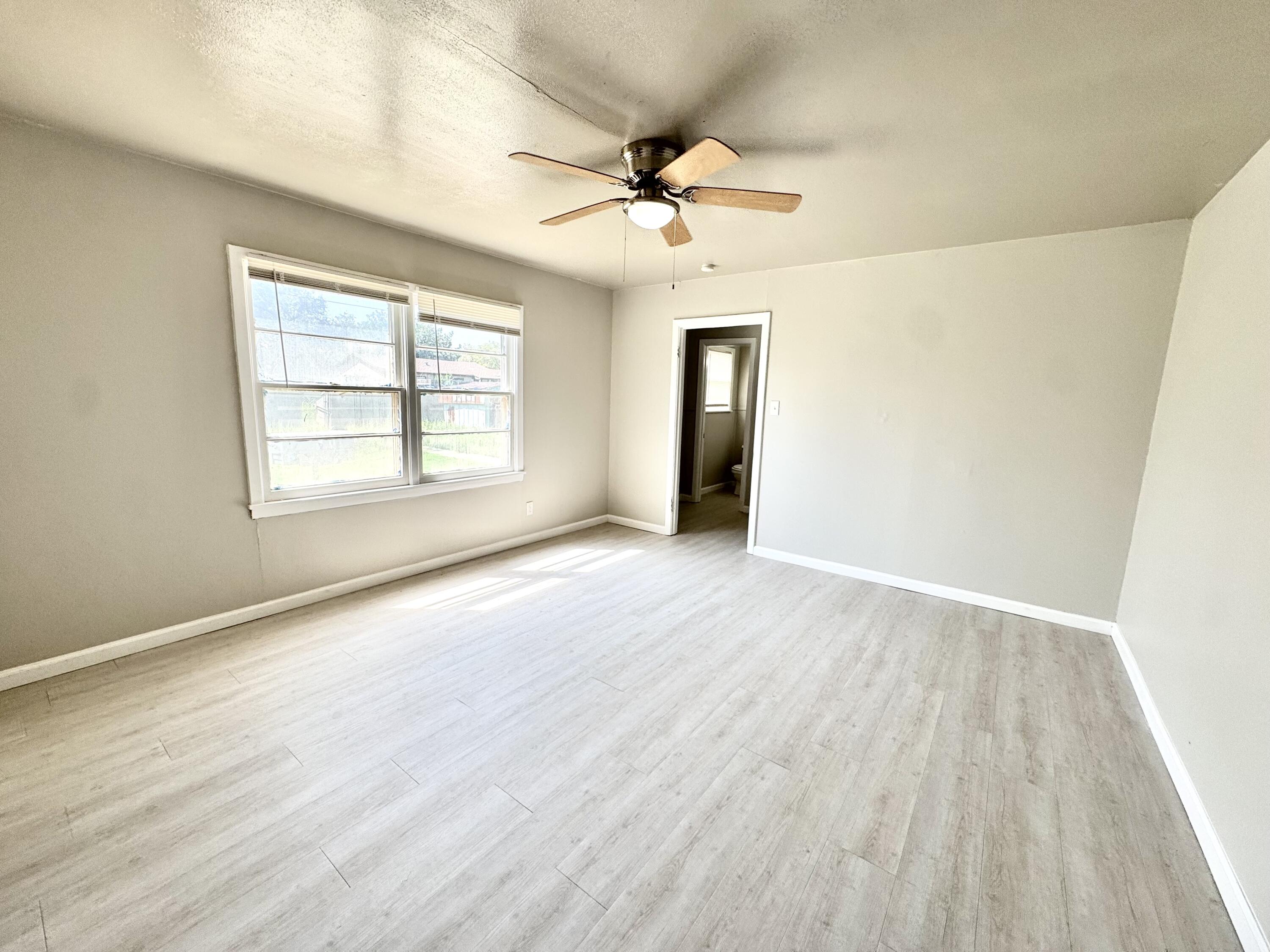 3805 35th Street Lubbock, TX 79413 - Photo 6 of 11 an empty room with wooden floor chandelier fan and windows