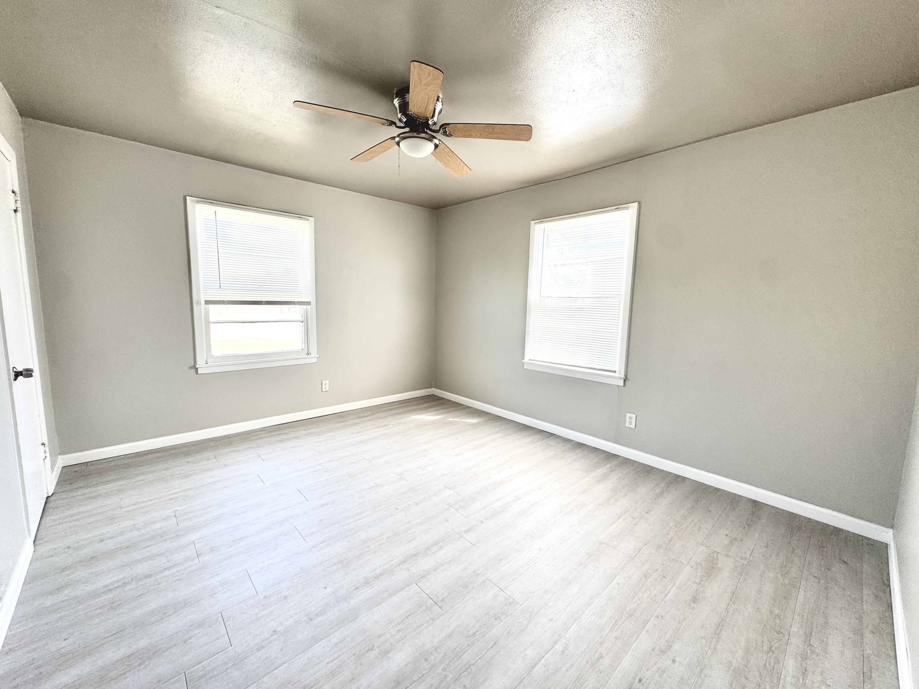 3805 35th Street Lubbock, TX 79413 - Photo 10 of 11 an empty room with wooden floor ceiling fan and windows