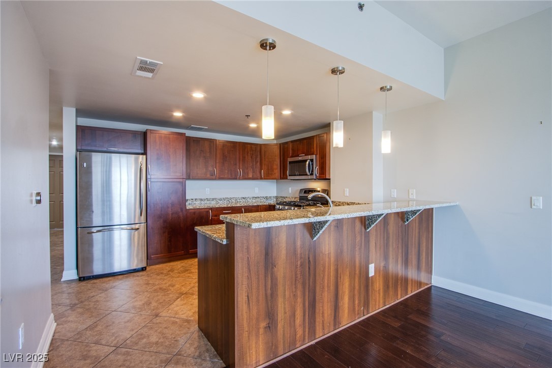 150 South Las Vegas Boulevard, Unit 1212 Las Vegas, NV 89101 - Photo 10 of 45 Kitchen featuring stainless steel appliances, a peninsula, light stone counters, baseboards, and recessed lighting