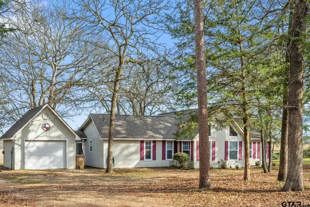 a view of a house with a yard covered by trees