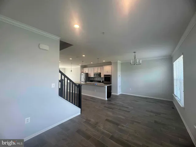 an empty room with wooden floor chandelier and windows