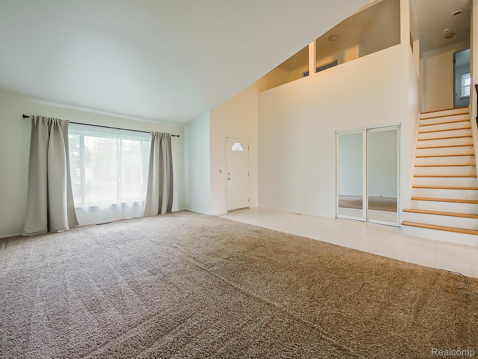 42195 Park Ridge Road Novi, MI 48375 - Photo 16 of 52 Vaulted ceiling with high-set windows, large window with natural light, light-toned carpeting, tiled flooring, and a wooden staircase
