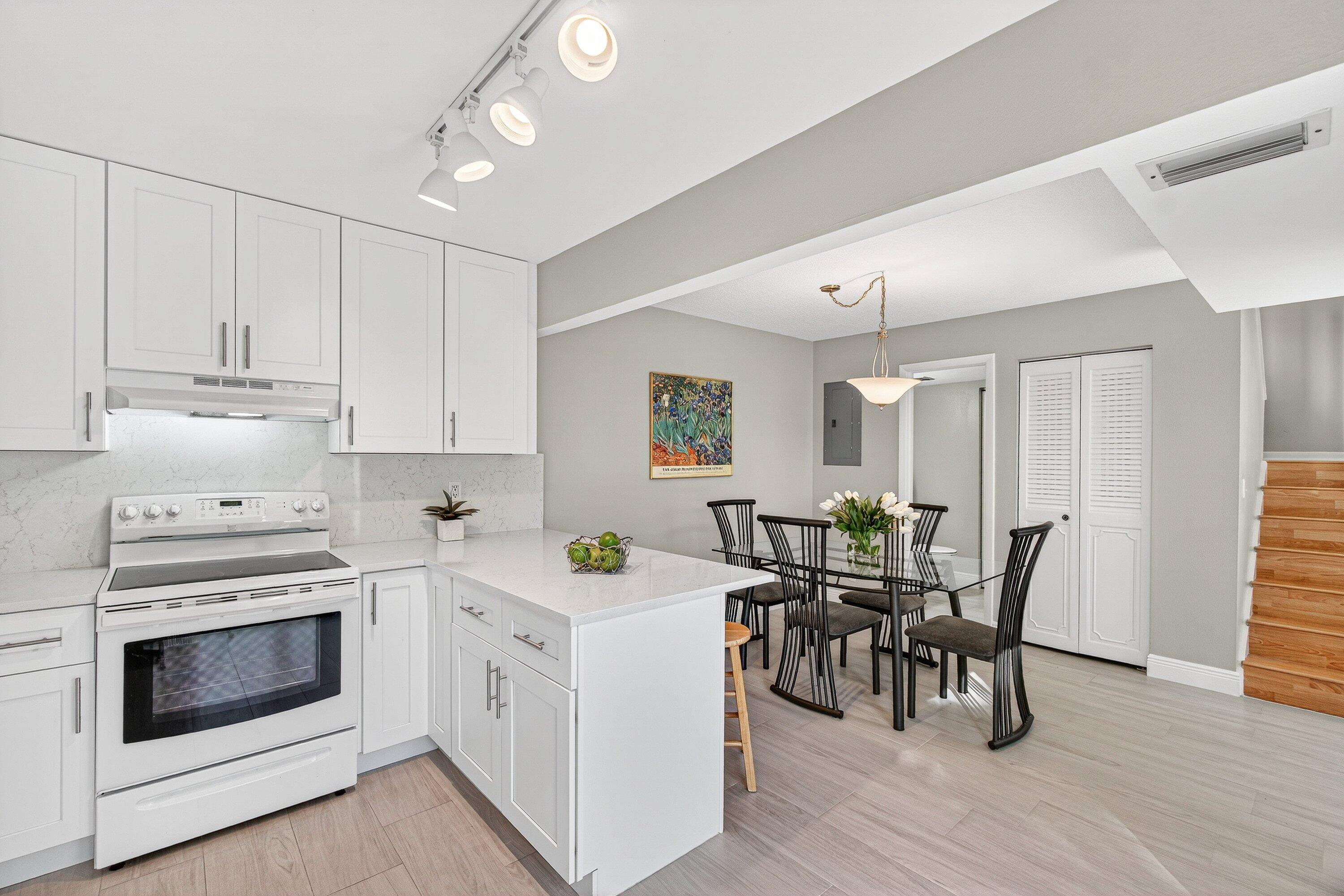 865 Northwest 29th Avenue, Unit D Delray Beach, FL 33445 - Photo 13 of 70 a kitchen with stainless steel appliances a white table chairs and a refrigerator