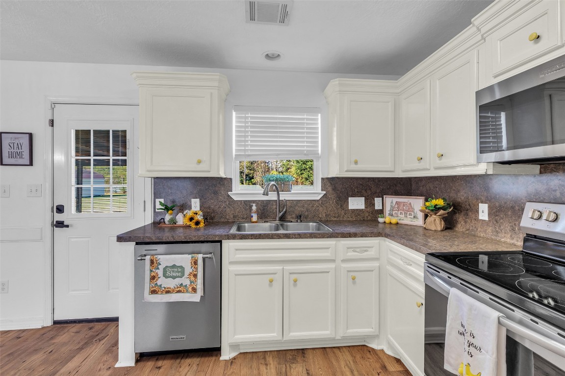 3862 Highline Oaks West Conroe, TX 77306 - Photo 12 of 23 a kitchen with stainless steel appliances white cabinets a stove a sink and a window