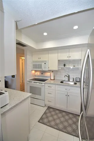 a kitchen with granite countertop white cabinets and white appliances