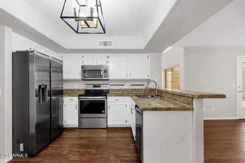 a kitchen with stainless steel appliances granite countertop a refrigerator a stove and a sink