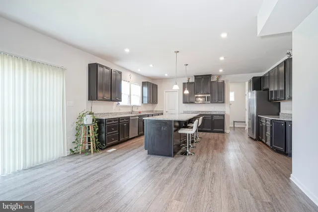 a kitchen with stainless steel appliances kitchen island granite countertop wooden floors and wooden cabinets
