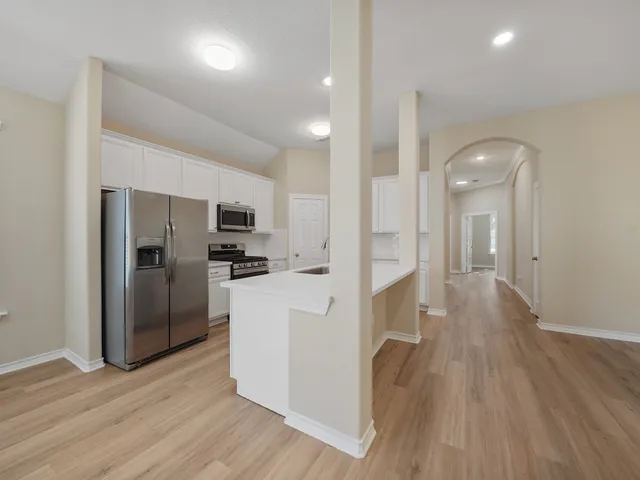 a view of a kitchen center island wooden floor and stainless steel appliances