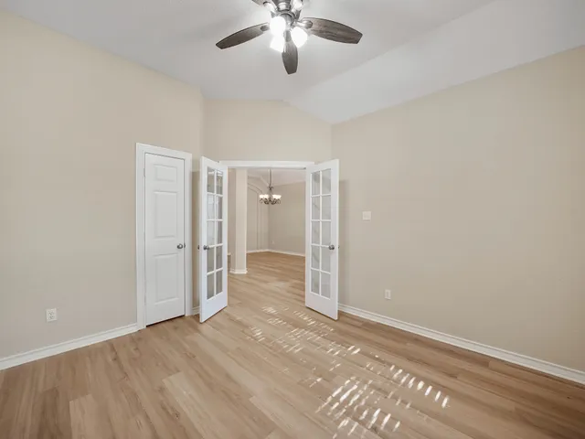 wooden floor in an empty room with a chandelier fan
