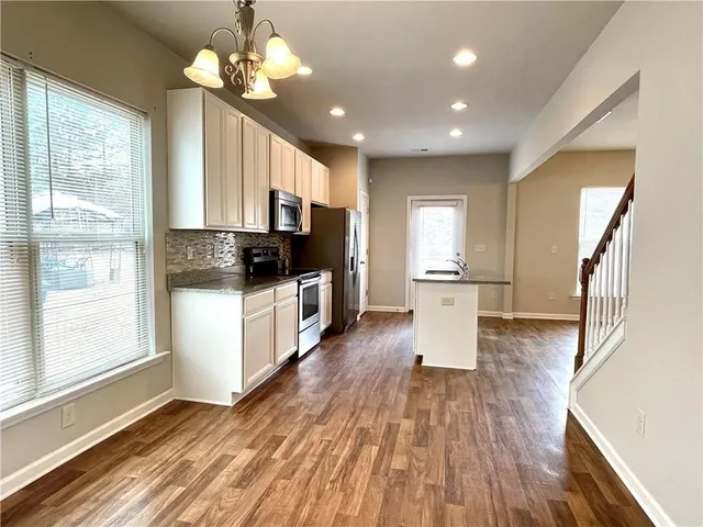 a kitchen with stainless steel appliances granite countertop a refrigerator a stove top oven a sink dishwasher and wooden floor