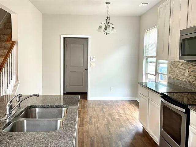 a kitchen with granite countertop a sink stainless steel appliances and cabinets