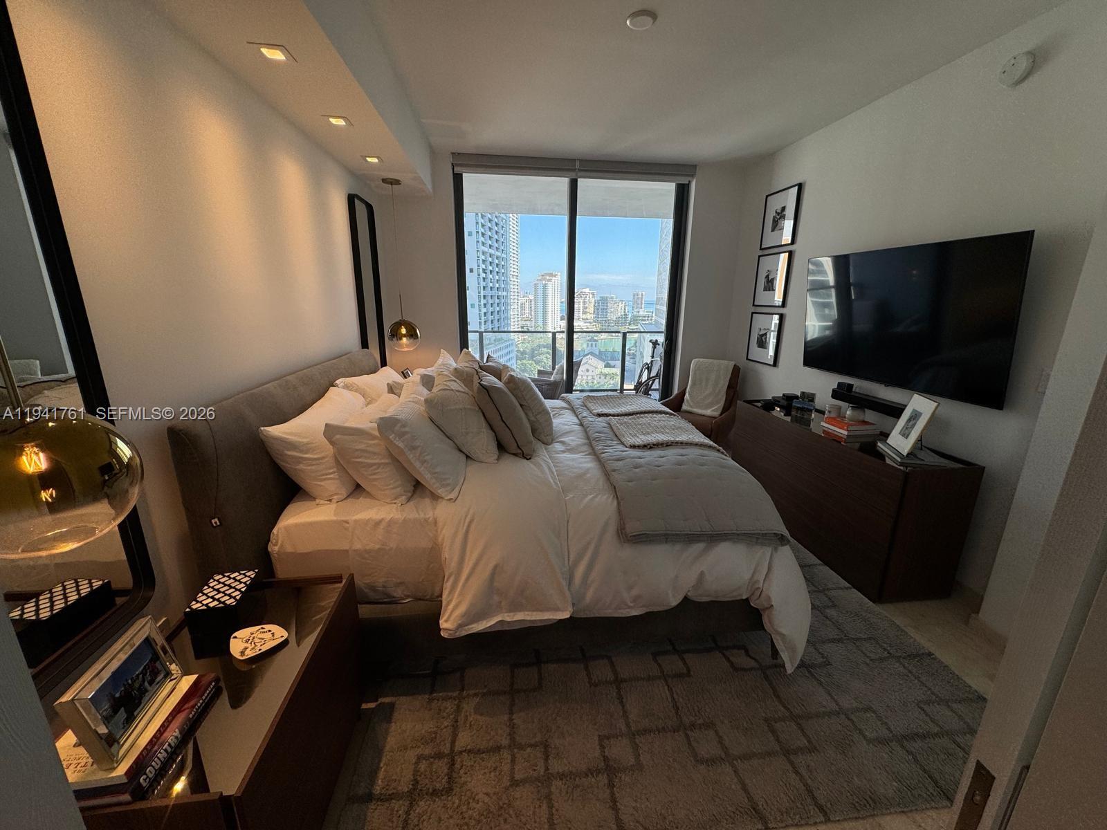 68 Southeast 6th Street, Unit 1109 Miami, FL 33131 - Photo 19 of 23 a bedroom with a bed and a flat tv screen on the dresser
