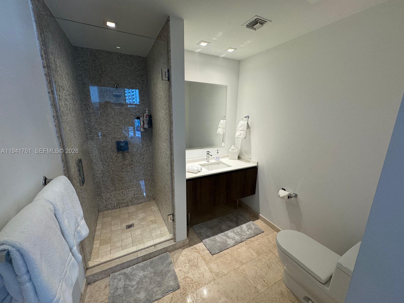 68 Southeast 6th Street, Unit 1109 Miami, FL 33131 - Photo 21 of 23 a bathroom with a shower sink and mirror