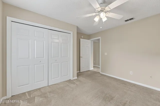 an empty room with closet and a chandelier fan