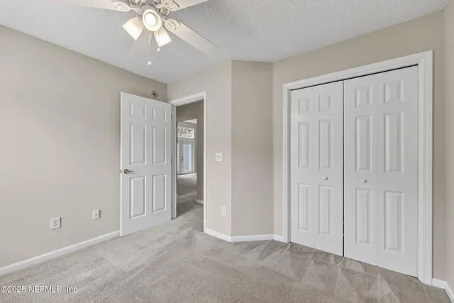 an empty room with windows closet and chandelier fan