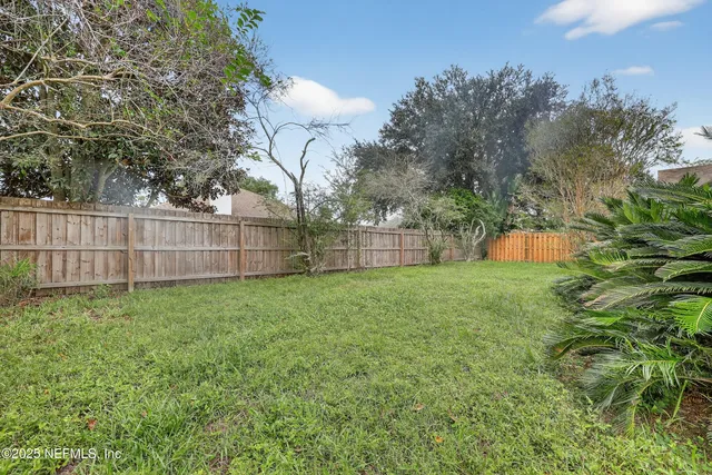 a view of a backyard with a large tree and wooden fence
