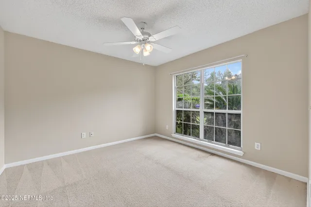 an empty room with a ceiling fan and a window