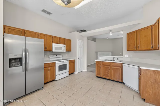 a large kitchen with stainless steel appliances granite countertop a stove a sink dishwasher and a refrigerator