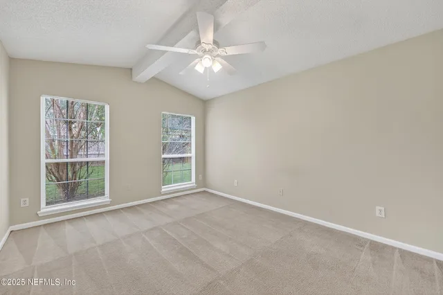 an empty room with windows and fan