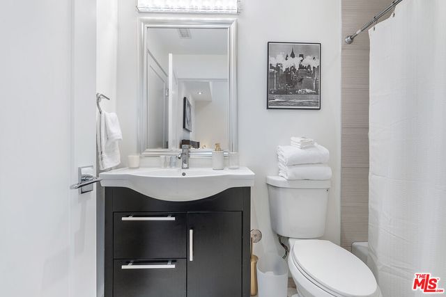a bathroom with a toilet sink vanity and mirror