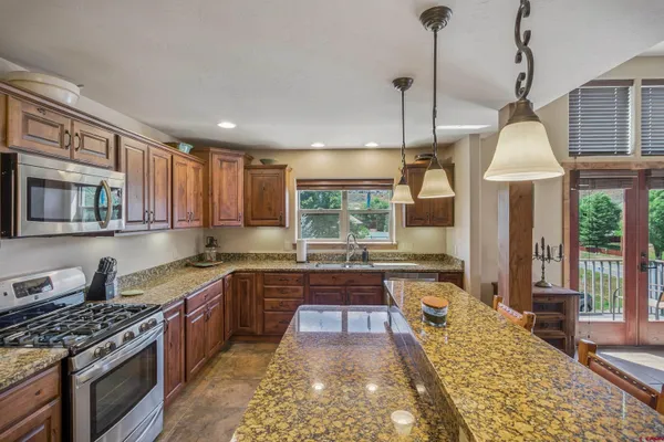 a kitchen with kitchen island a counter top space a refrigerator and a view of living room