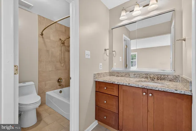 a bathroom with a granite countertop sink a toilet and a mirror