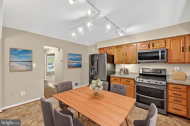 a kitchen with a sink a stove a refrigerator cabinets and a dining table