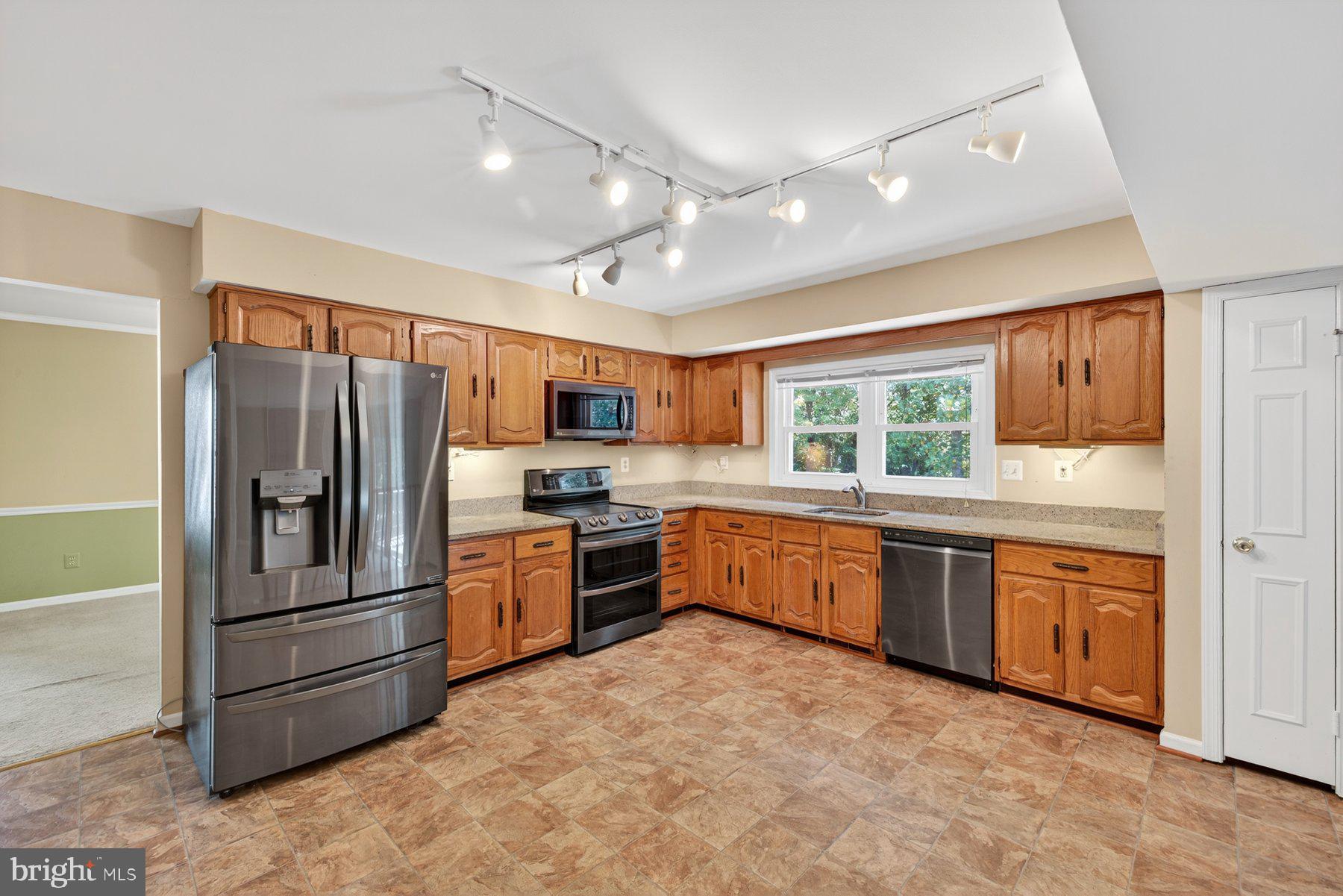 8537 Hooes Road Springfield, VA 22153 - Photo 9 of 30 a large kitchen with stainless steel appliances granite countertop a refrigerator a stove a sink a island with wooden cabinets and floor