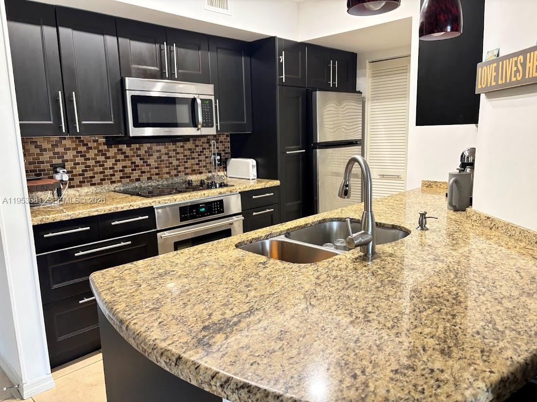 a kitchen with granite countertop a sink and stainless steel appliances