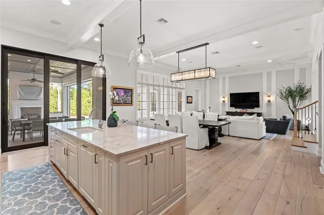 a large kitchen with stainless steel appliances a center island wooden floor and a view of living room