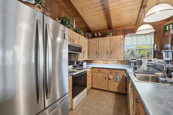 a kitchen with stainless steel appliances granite countertop a refrigerator a sink a stove and a refrigerator with wooden floors