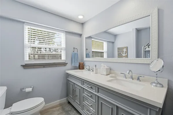 a bathroom with a granite countertop sink a toilet a mirror and a window