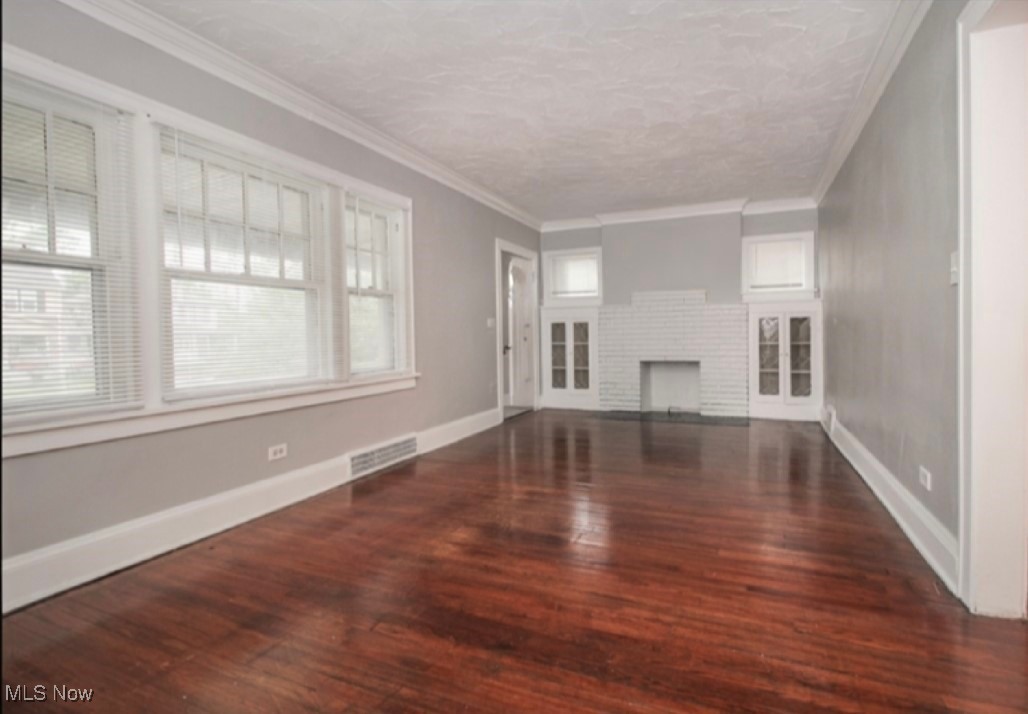 3397 Silsby Road Cleveland, OH 44118 - Photo 3 of 12 Unfurnished living room featuring a wealth of natural light, visible vents, ornamental molding, and wood finished floors