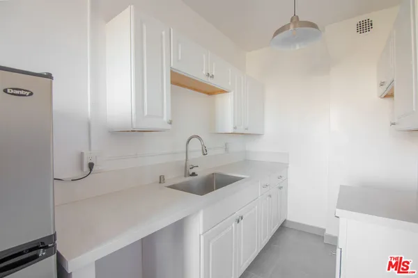 a kitchen with a sink dishwasher and white cabinets with wooden floor