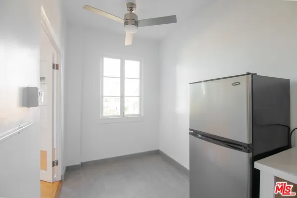 an empty room with a refrigerator and windows