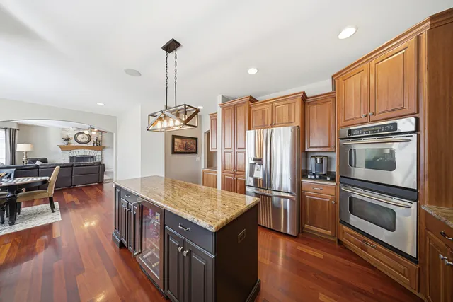 a living room with stainless steel appliances granite countertop furniture wooden floor and a kitchen view
